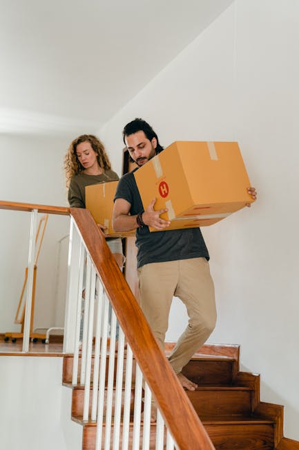 Close-up view of three brown cardboard boxes stacked inside a property, with the top box labeled 'STUFF' in red marker and featuring a small smiley face, and the lower box labeled 'CLOTHES' also handw